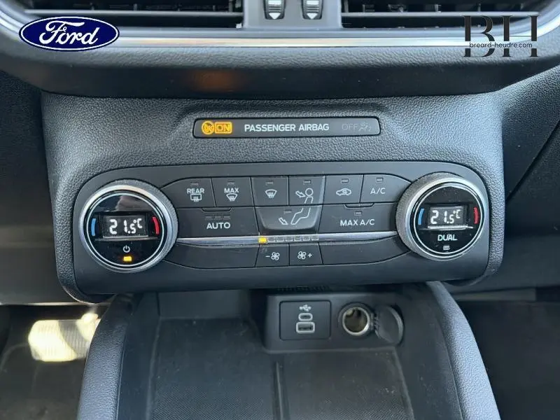Vue rapprochée du tableau de bord du Ford Kuga 2023, montrant les commandes de climatisation à 21,5°C en mode dual.