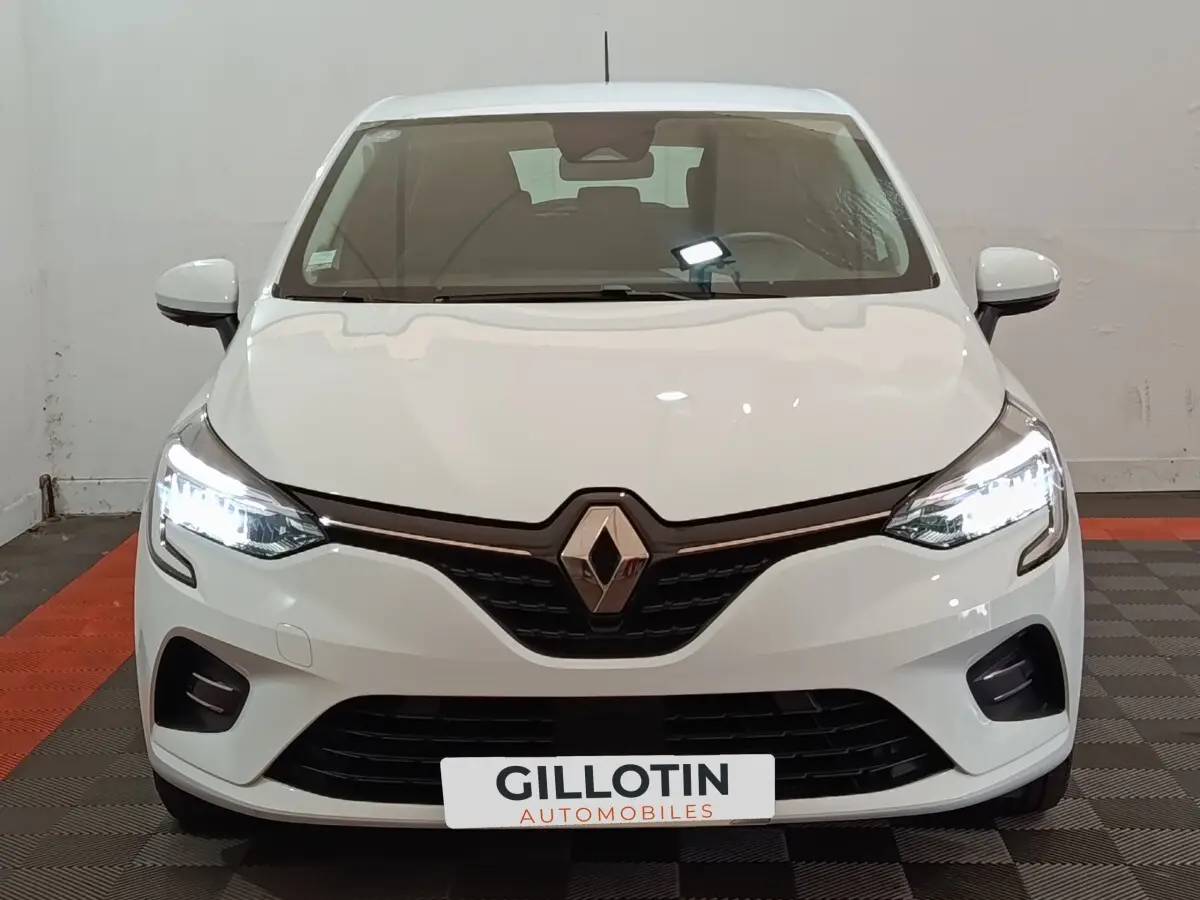 Vue de face d'une Renault Clio Business E-TECH 140 blanche avec phares LED allumés et calandre noire.