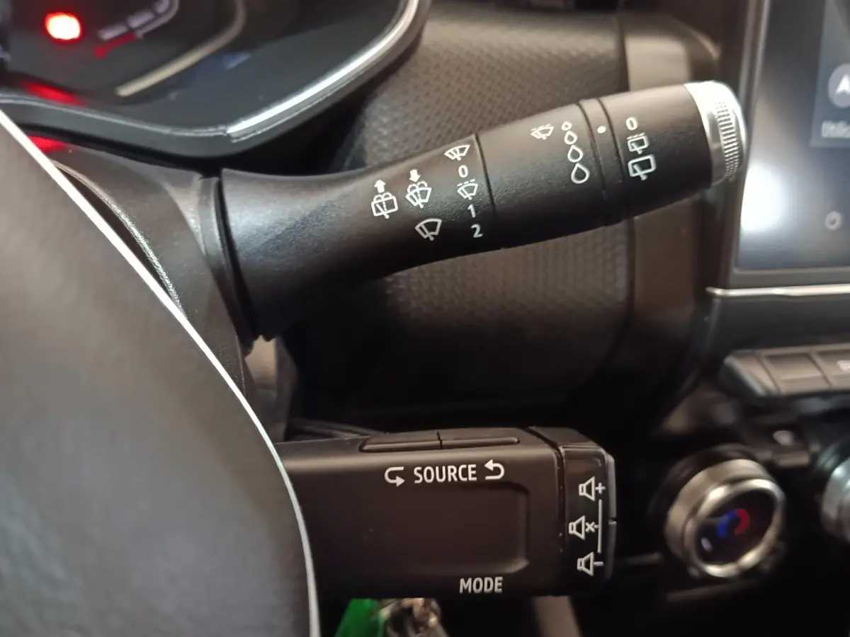 Gros plan sur les commandes au volant de la Renault Clio Business E-TECH 140 blanche, avec boutons source et essuie-glace.