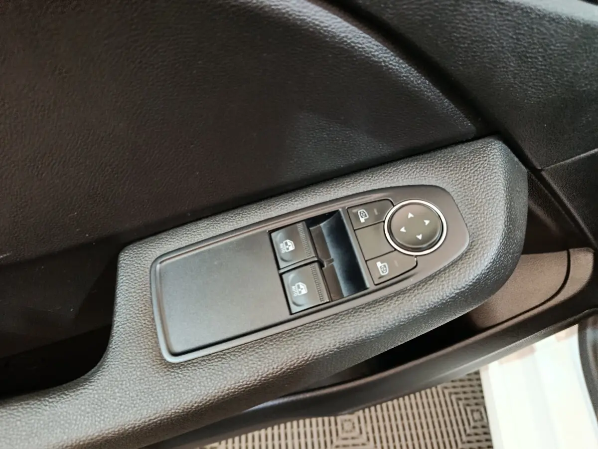 Commande des vitres électriques et réglage des rétroviseurs sur la porte côté conducteur d'une Renault Clio blanche.