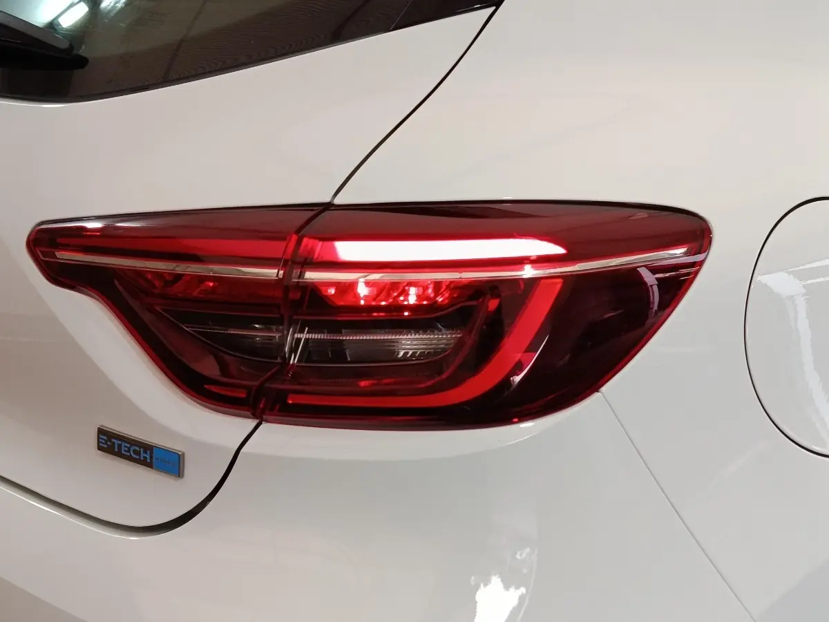 Gros plan sur le feu arrière droit rouge d’une Renault Clio Business E-TECH 140 blanche avec logo hybride.