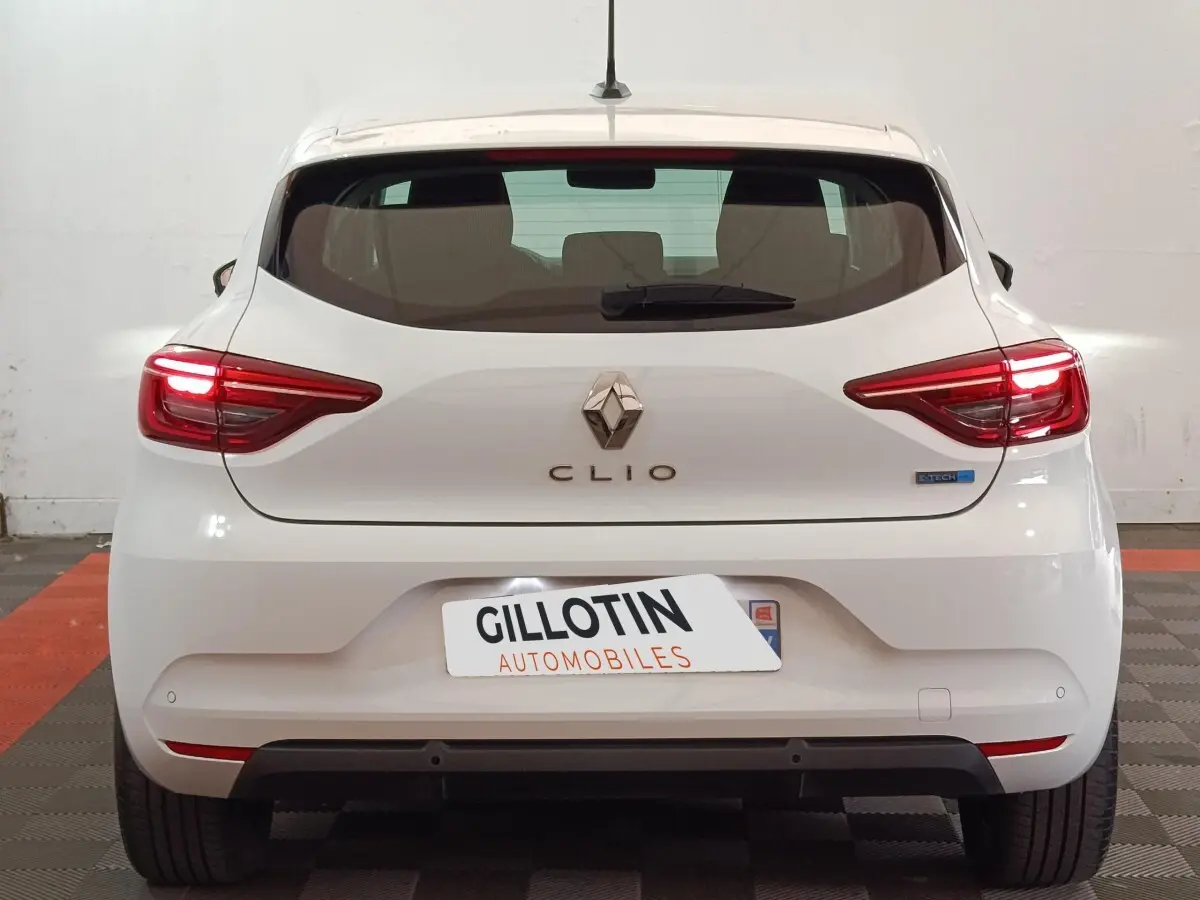 Vue arrière d'une Renault Clio Business E-TECH 140 blanche avec feux LED allumés et logo distinctif E-TECH.