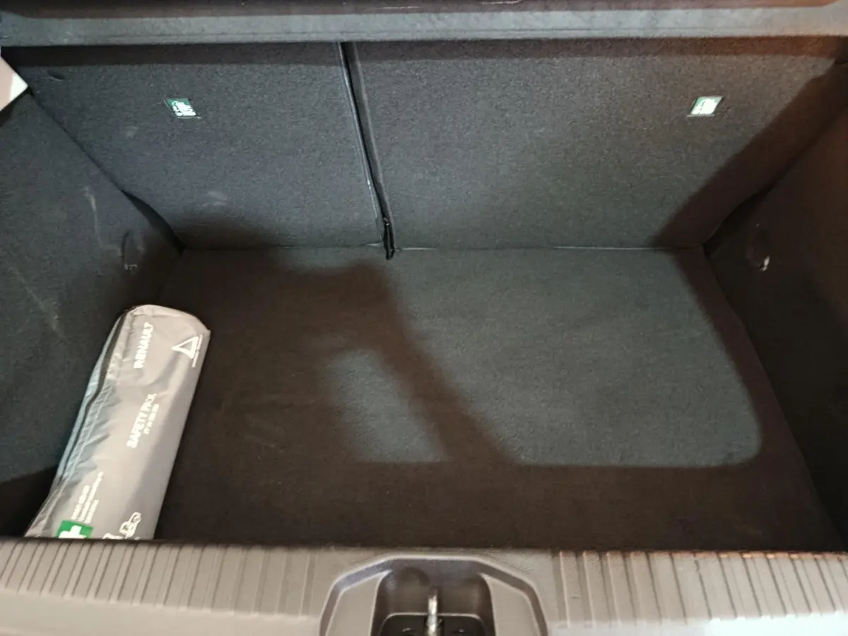 Coffre vide vu de dessus de la Renault Clio Business E-TECH 140 blanc, avec trousse de secours à gauche.