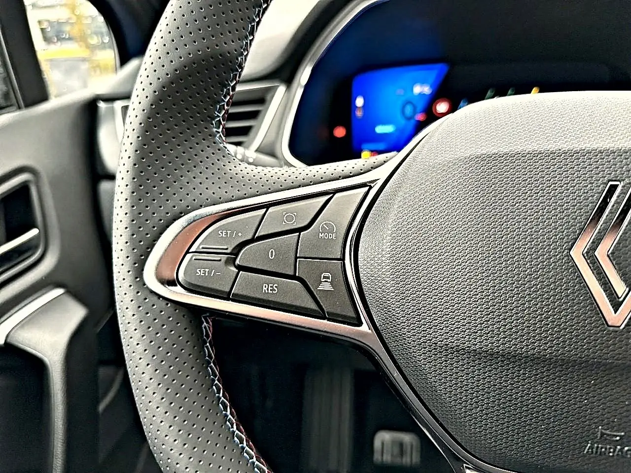 Gros plan sur le volant perforé côté gauche de la Renault Symbioz 2026 bleu iron avec commandes multifonctions.