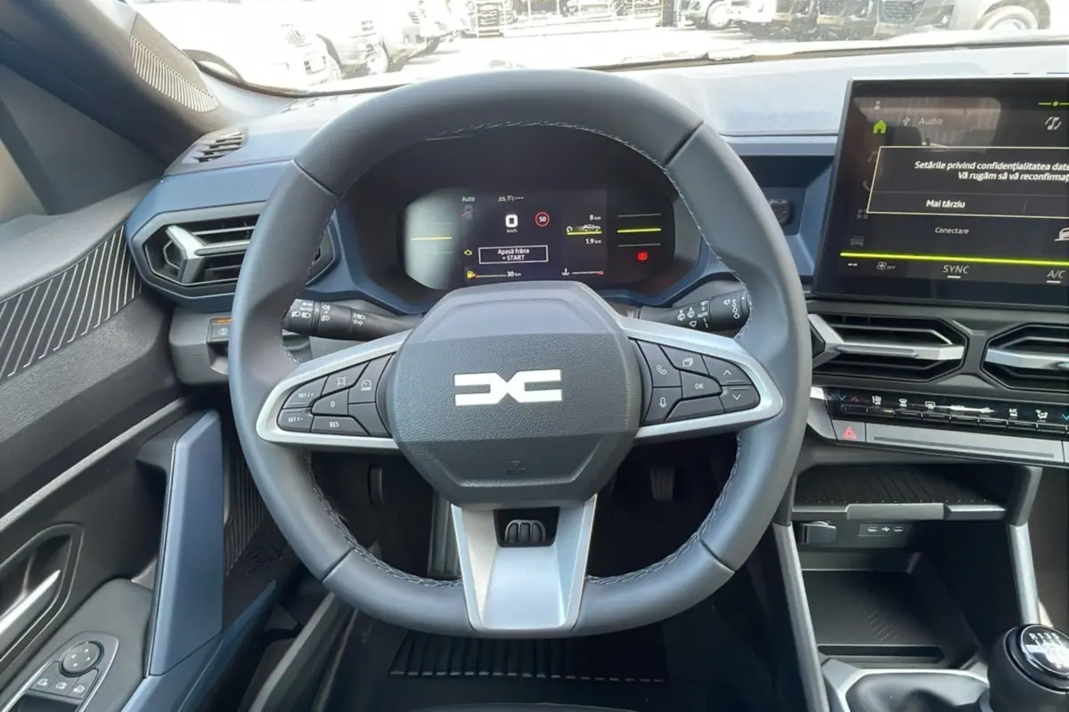 Vue intérieure centrée sur le volant multifonction du Dacia Bigster 2025 avec tableau de bord numérique et écran tactile.