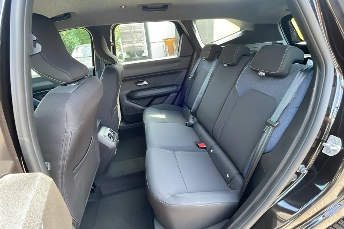 Vue intérieure sur la banquette arrière du Dacia Bigster 2025 noir perle, avec sièges tissu noir et ceinture grise.