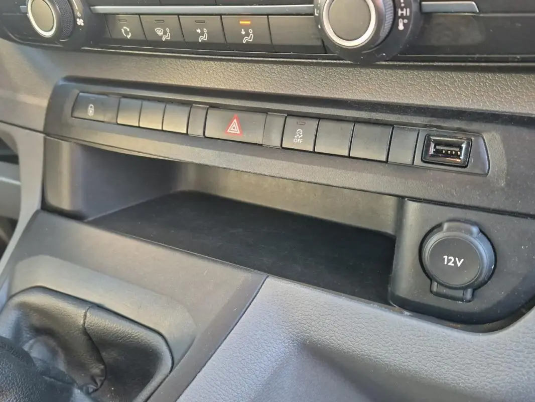 Détail de la console centrale du Citroën Jumpy blanc 2019, avec commandes climatisation et prise 12V visible.