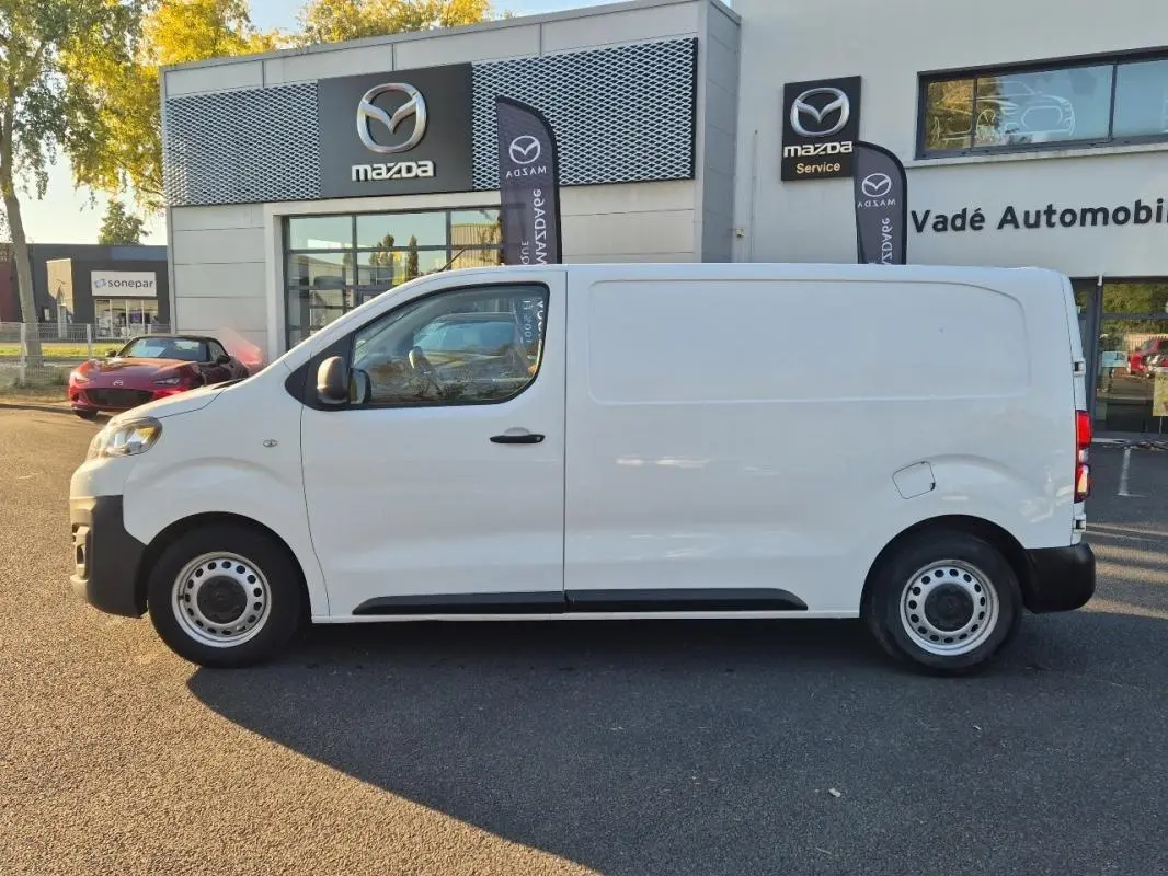 Vue de profil côté gauche d'un Citroën Jumpy blanc 2019, fourgon utilitaire devant un concessionnaire Mazda.