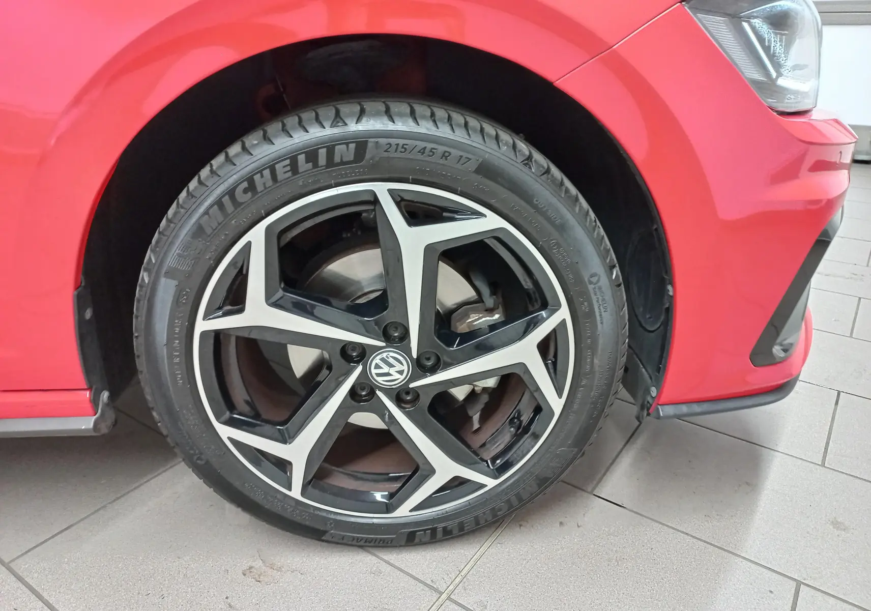 Gros plan sur la roue avant gauche d'une Volkswagen Polo Rouge Flash avec jante alliage R-Line distinctive.