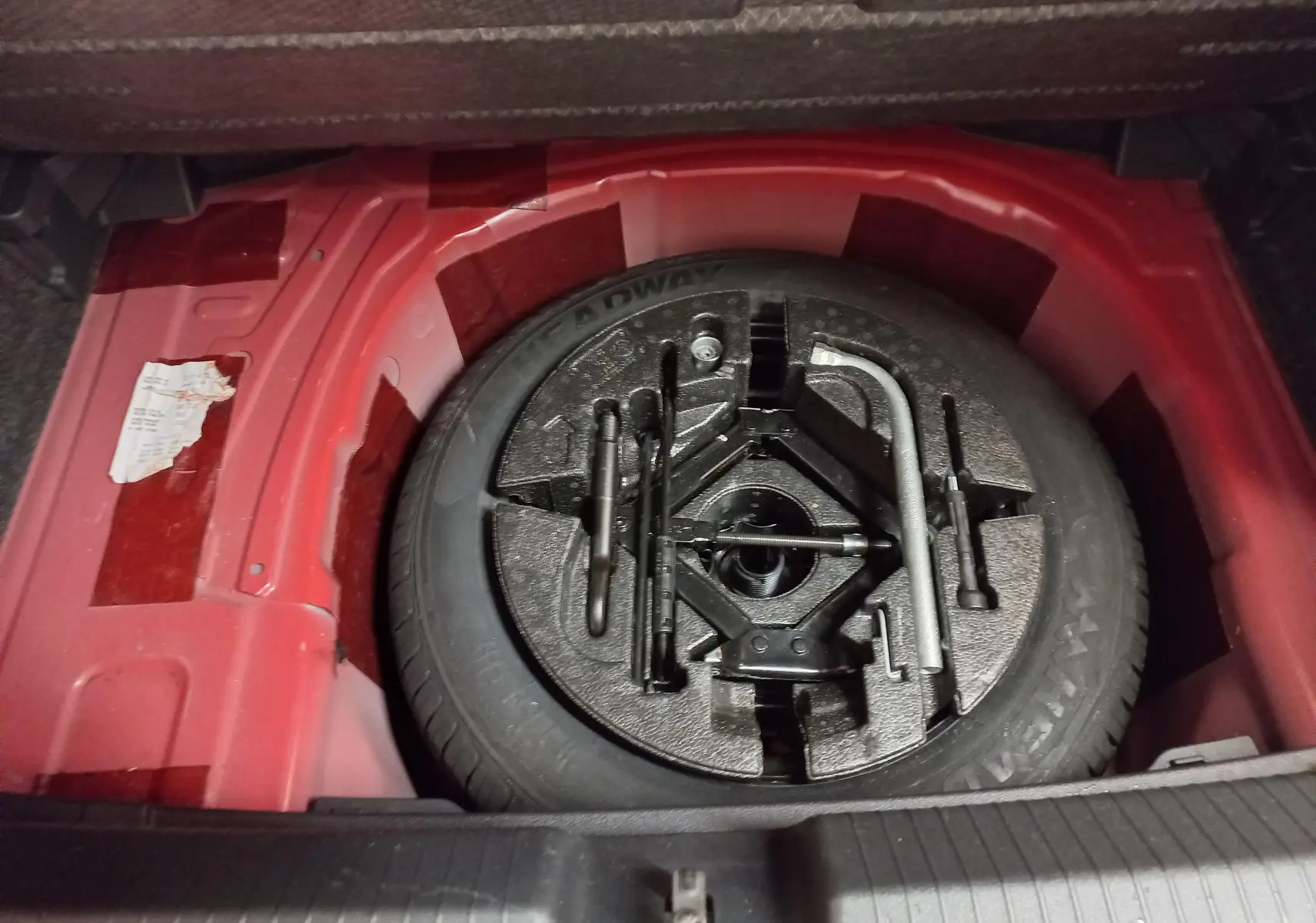 Roue de secours avec outils de changement dans le coffre rouge flash d'une Volkswagen Polo 2019 R-Line.