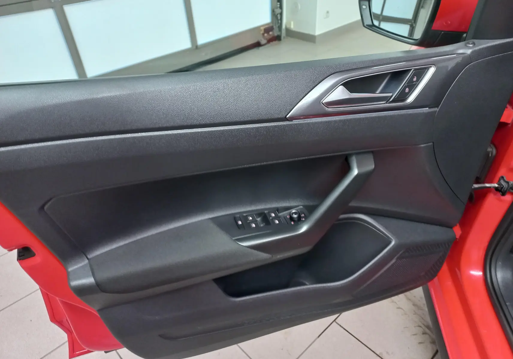 Vue intérieure de la porte côté gauche rouge flash d'une Volkswagen Polo 2019 avec commandes de vitres et verrouillage.