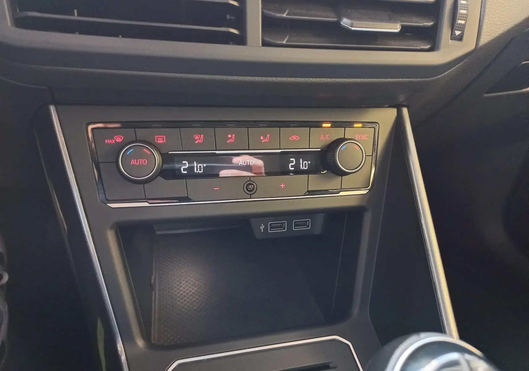 Gros plan sur la console centrale de la Volkswagen Polo Rouge Flash, avec commandes climatisation et ports USB visibles.