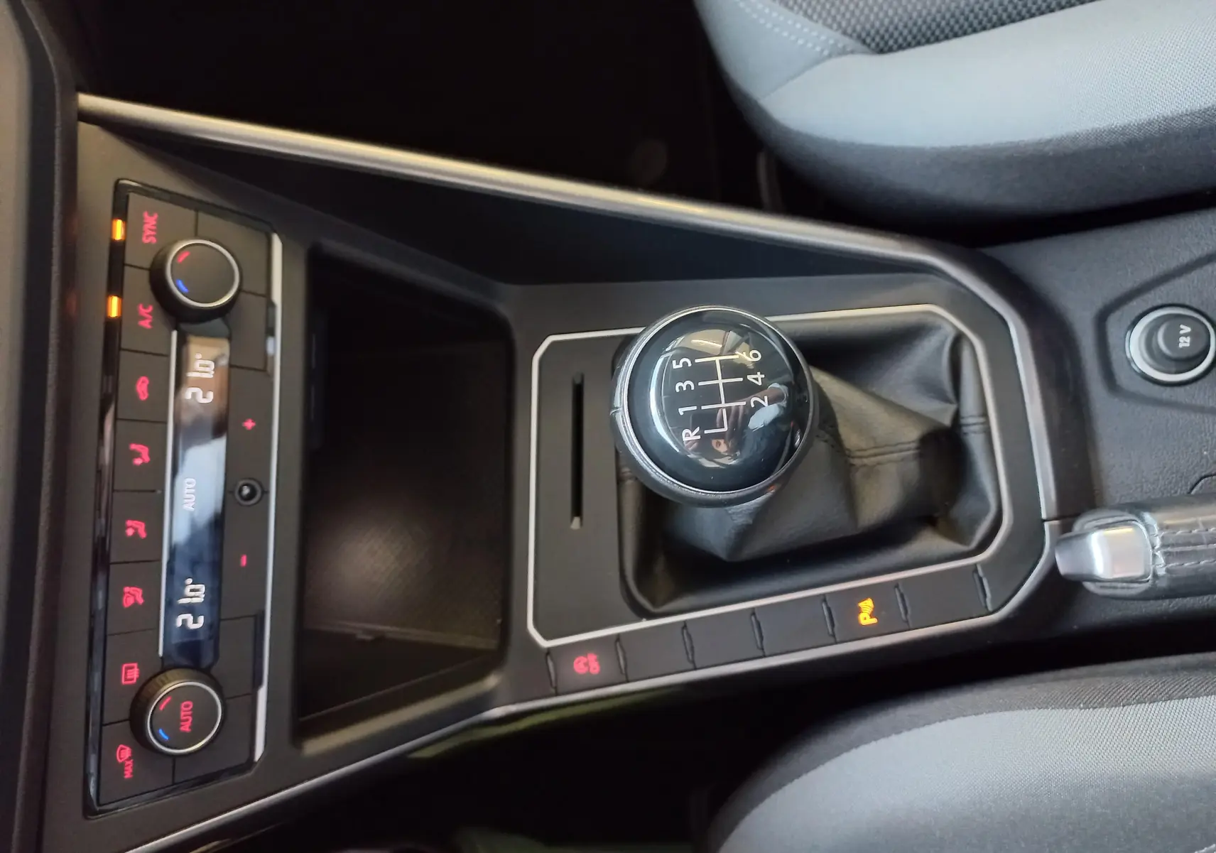 Vue rapprochée de la console centrale d'une Volkswagen Polo Rouge Flash 2019, mettant en valeur le levier de vitesses manuel et les commandes climatiques.