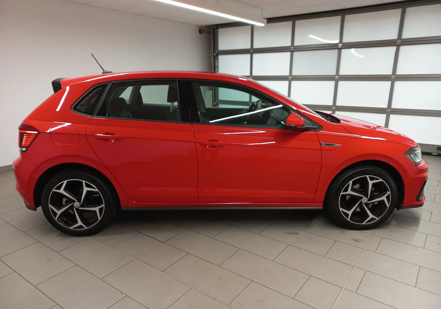 Profil droit d'une Volkswagen Polo 1.0 TSI 115 R-Line rouge Flash, avec jantes alliage et intérieur visible.
