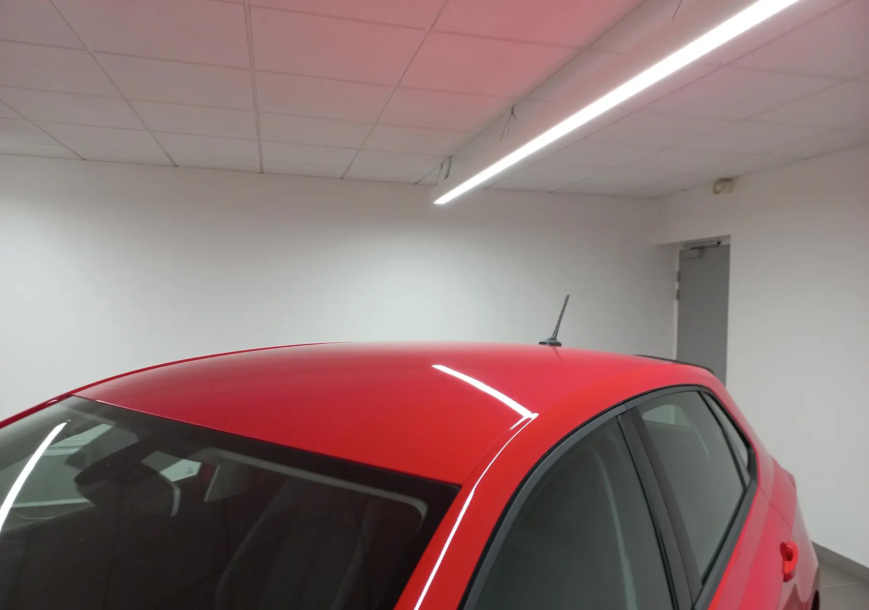 Vue 3/4 arrière droit d'une Volkswagen Polo Rouge Flash 2019 avec antenne de toit en intérieur blanc.