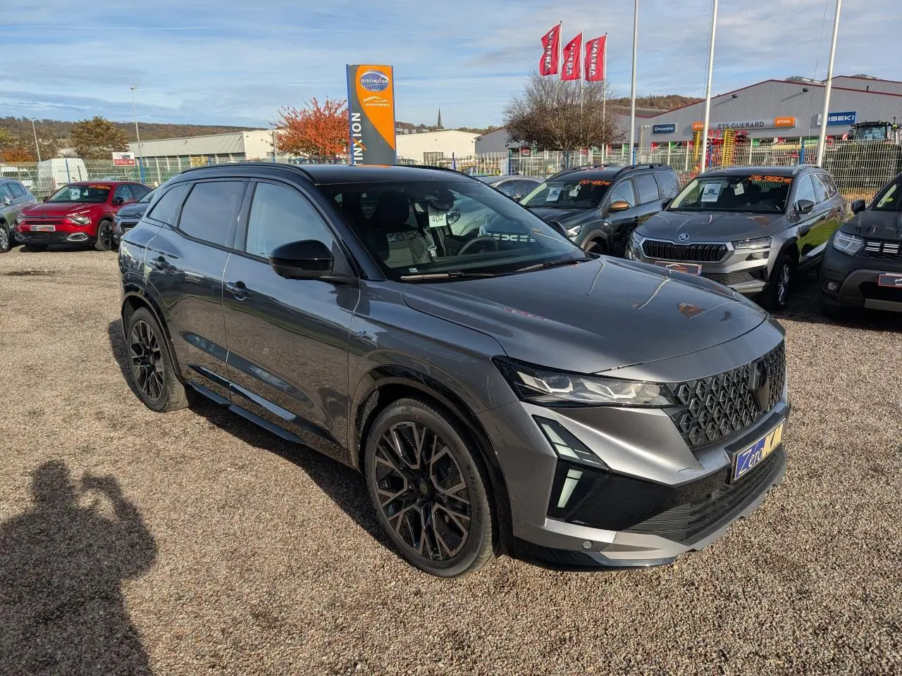 Renault Austral gris métallisé en 3/4 avant droit, avec jantes noires et toit noir étoilé visible en extérieur.