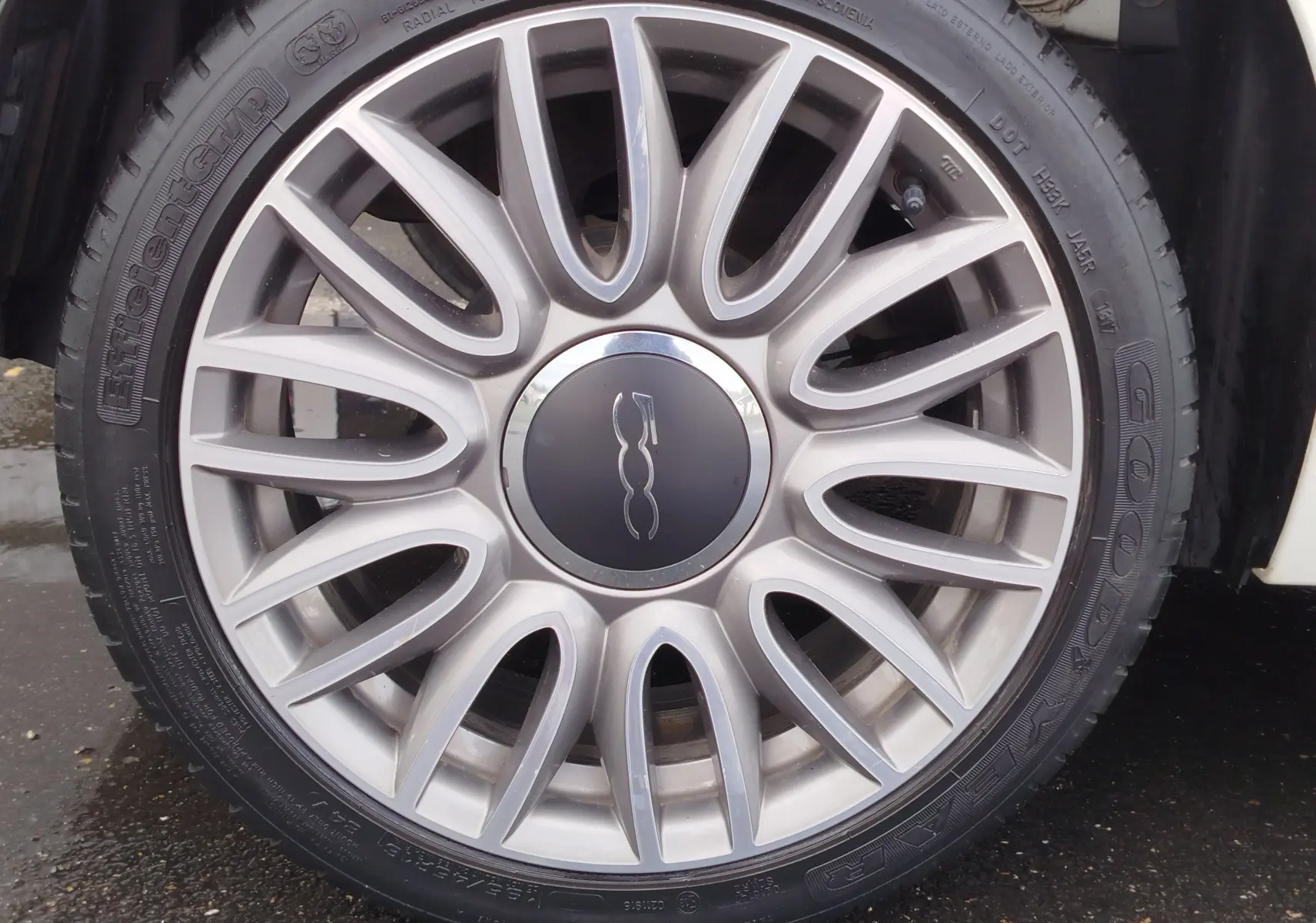 Gros plan sur la jante argentée en alliage de la Fiat 500 blanche, mettant en valeur le logo central distinctif.