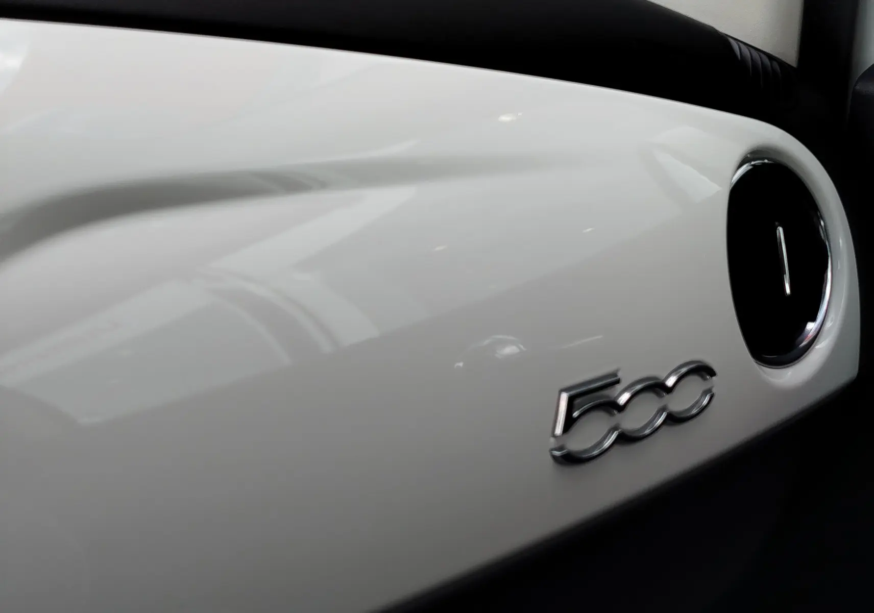 Gros plan sur le tableau de bord blanc Bossa Nova de la Fiat 500 2017 avec logo 500 chromé et sortie d'air ronde noire.