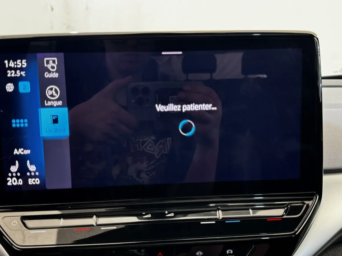 Écran tactile central du tableau de bord du Volkswagen ID.4 blanc, affichant un message "Veuillez patienter..."