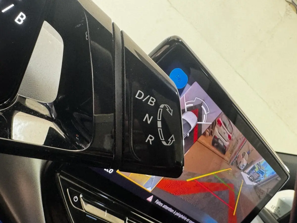 Gros plan sur le levier de vitesses noir et l'écran tactile affichant la caméra de recul dans un Volkswagen ID.4 blanc.