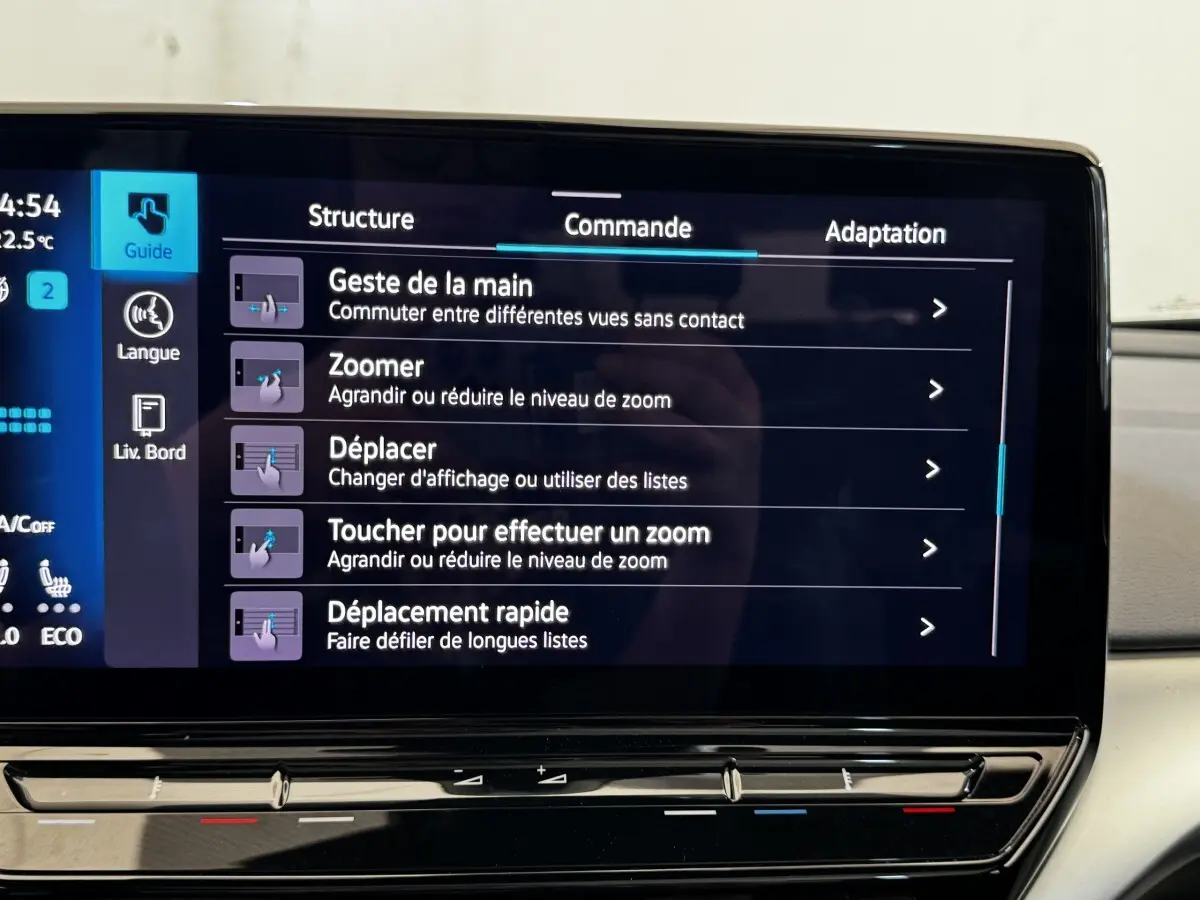 Vue de face intérieure du tableau de bord du Volkswagen ID.4 blanc avec écran tactile affichant les commandes de zoom et déplacement.