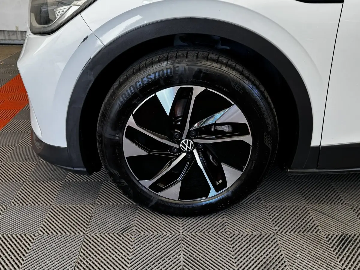 Gros plan sur la roue avant gauche blanche d’un Volkswagen ID.4 avec jante noire et argentée au design moderne.