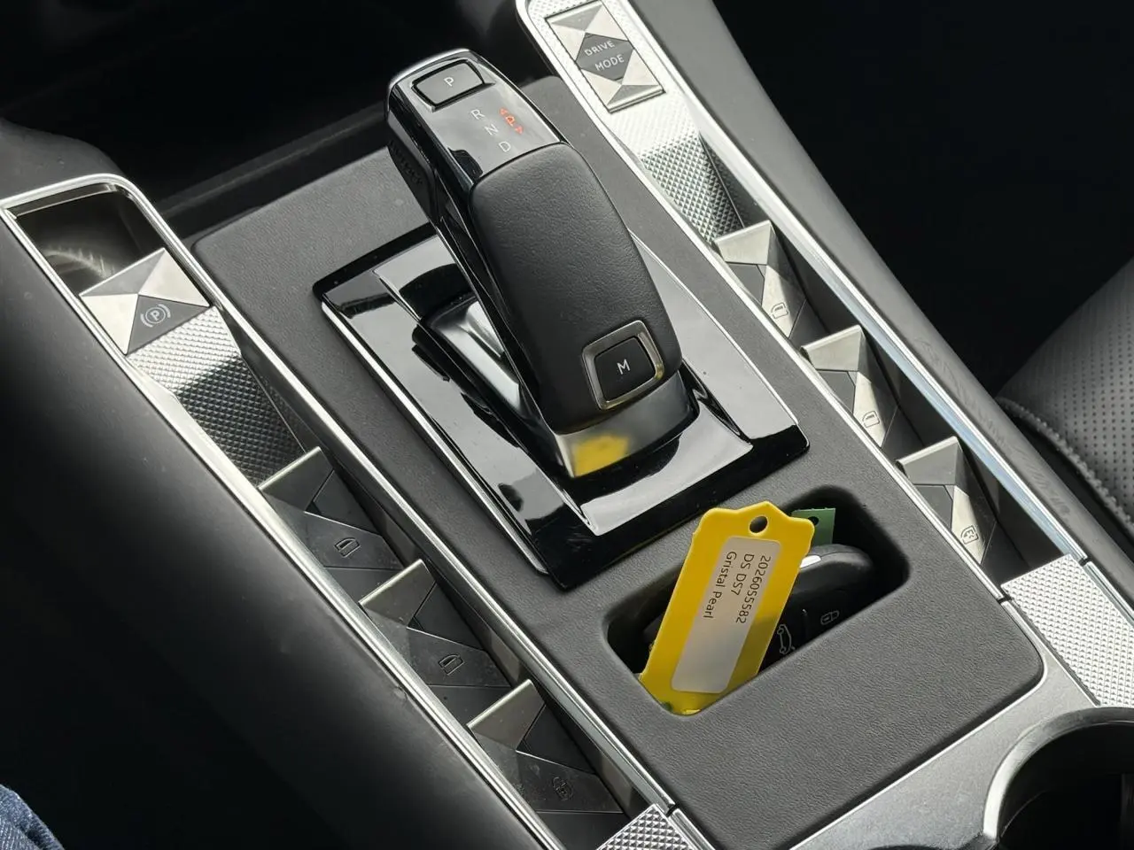 Gros plan sur la console centrale noire du DS7 1.5 BlueHDI avec levier de vitesses automatique et clé avec étiquette jaune Cristal Pearl.