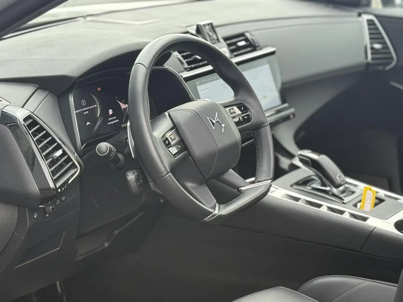Intérieur noir du DS7 2025 vu côté conducteur, volant cuir avec commandes et écran tactile central visible.