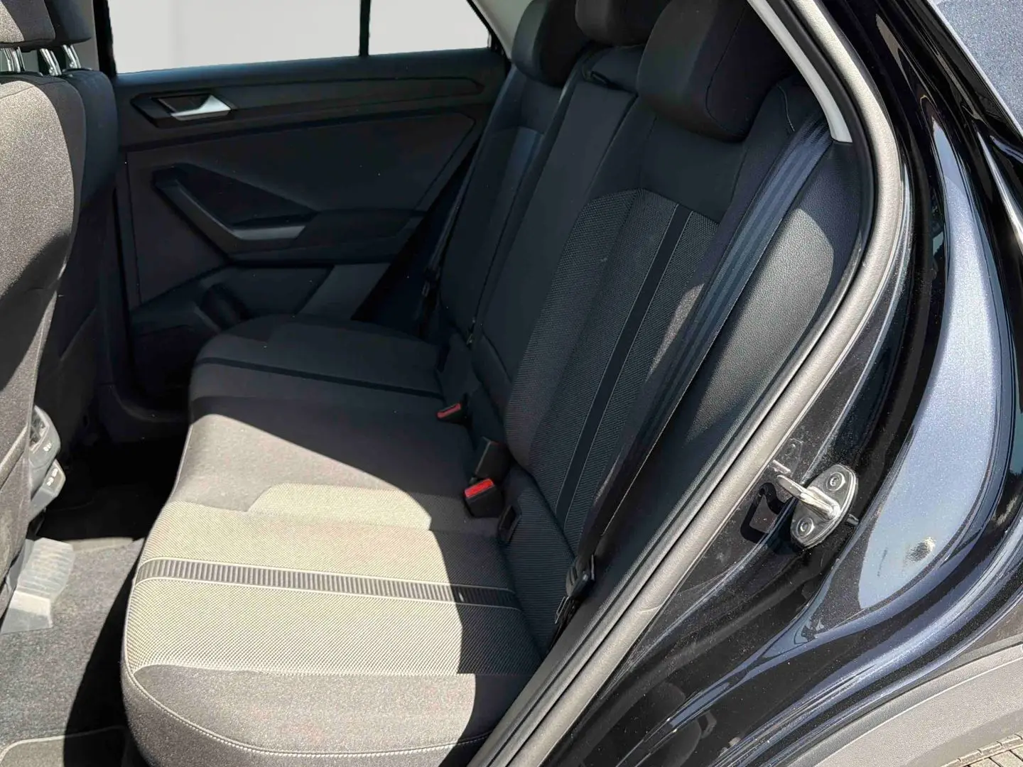 Vue intérieure arrière côté droit du Volkswagen T-Roc noir, montrant les sièges arrière en tissu gris foncé.