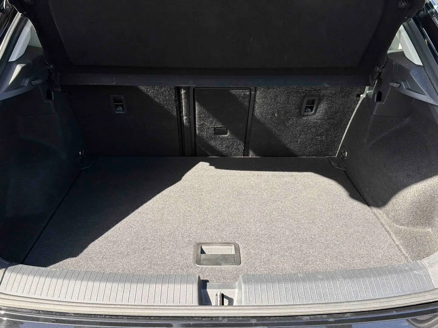 Coffre ouvert du Volkswagen T-Roc noir 2025, vue de l'arrière montrant l'espace de chargement vide et le revêtement intérieur.