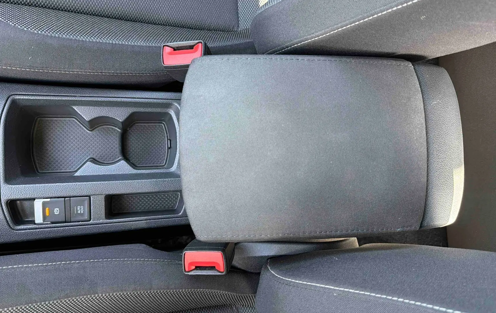 Vue plongeante sur l'accoudoir central noir et les sièges en tissu gris du Volkswagen T-Roc 2025.