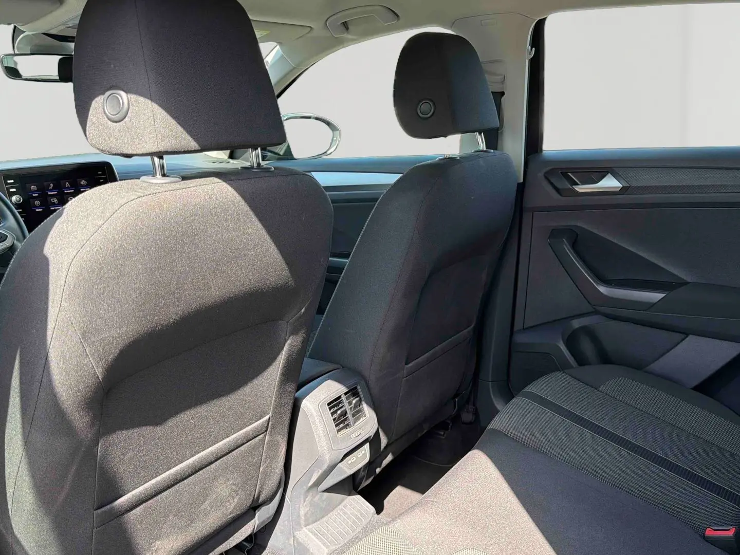 Vue arrière intérieure du Volkswagen T-Roc noir 2025, montrant les sièges avant et la banquette arrière en tissu.