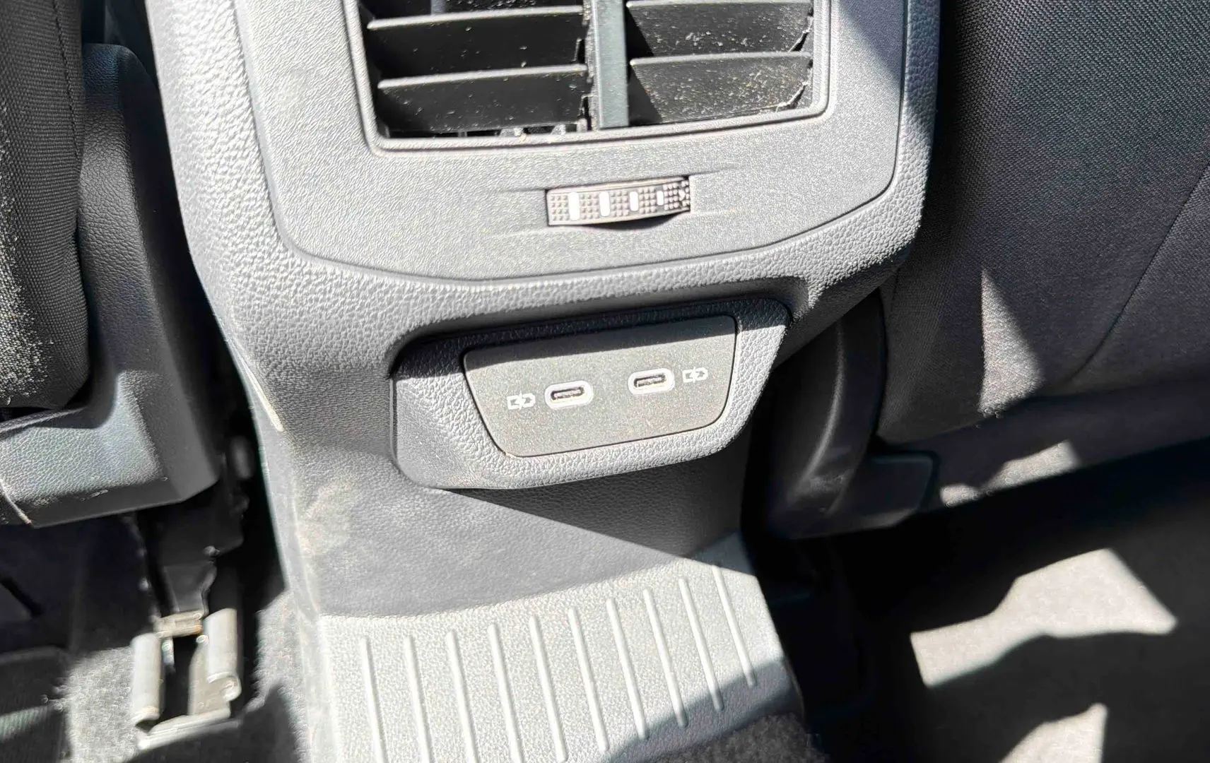 Prise USB-C double et bouche d’aération arrière dans l’habitacle du Volkswagen T-Roc noir, vue côté arrière passager.