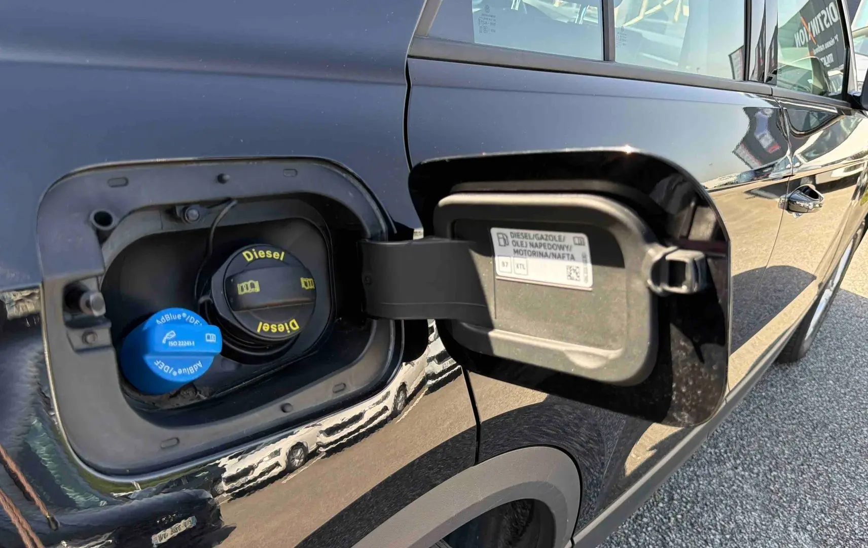 Vue rapprochée de la trappe à carburant ouverte côté gauche d’un Volkswagen T-Roc noir diesel.