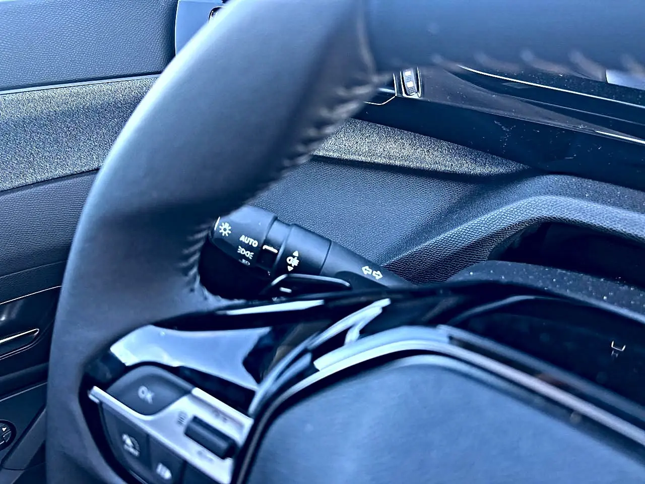 Gros plan sur le volant multifonction noir et la commande des phares à gauche dans l’habitacle d’une Peugeot 308.