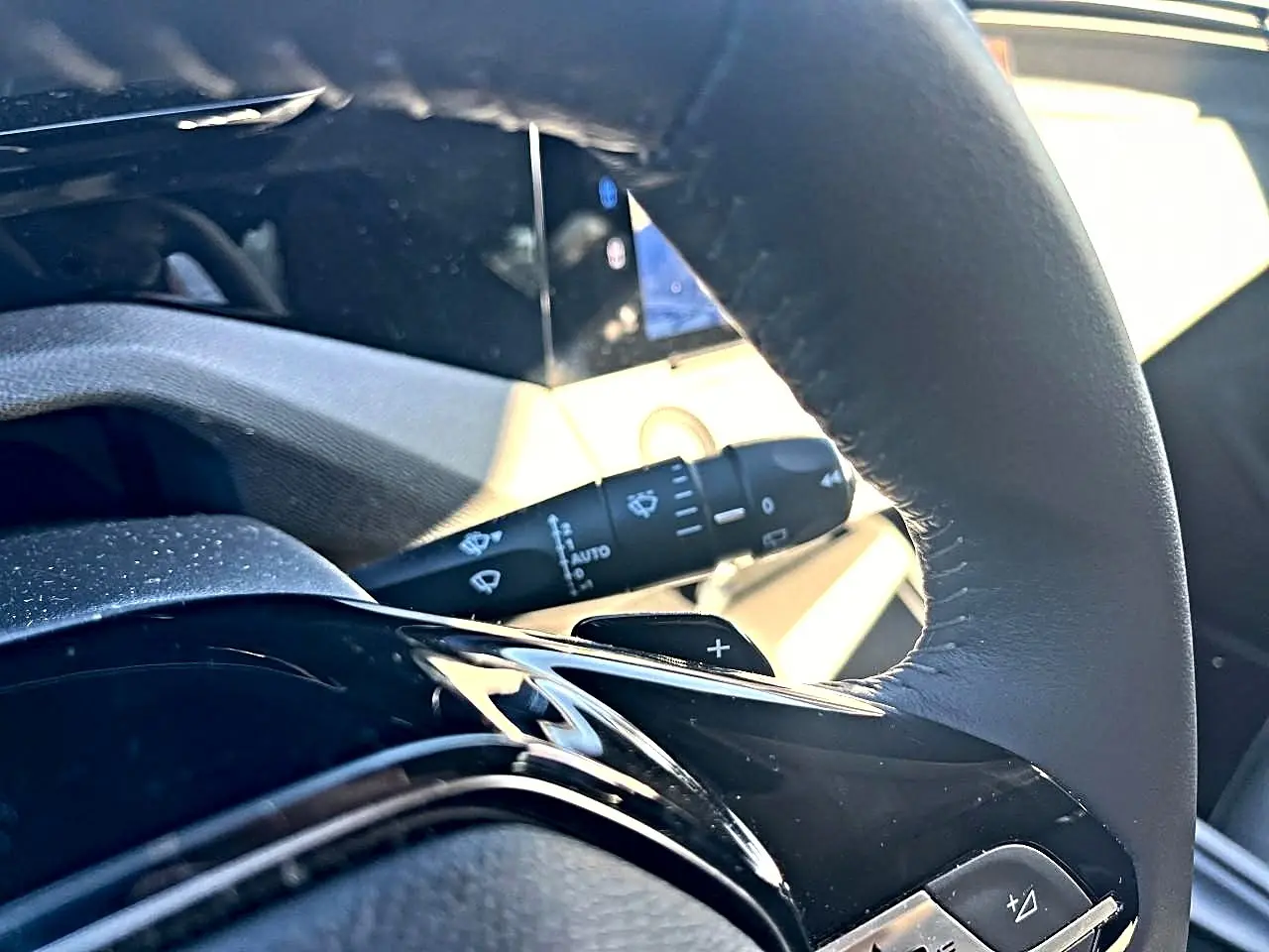 Gros plan sur le volant noir de la Peugeot 308 gris selenium, avec commandes multifonctions et palettes au volant visibles.
