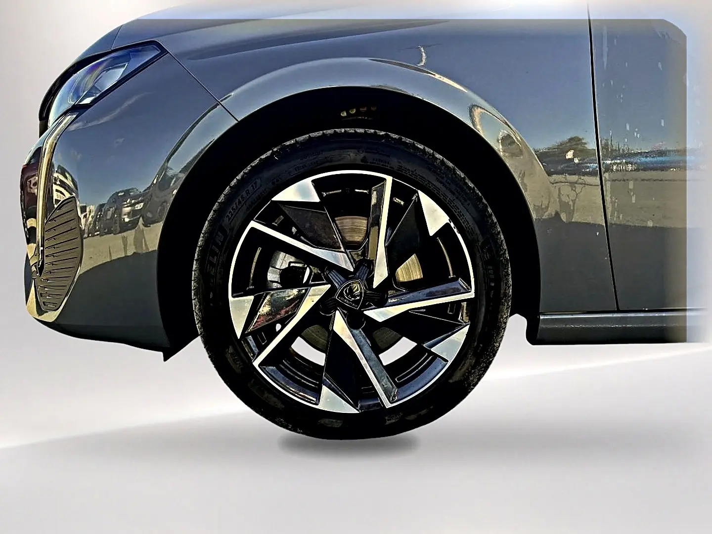 Gros plan sur la roue avant gauche et l'aile d'une Peugeot 308 gris selenium avec jante alu au design moderne.