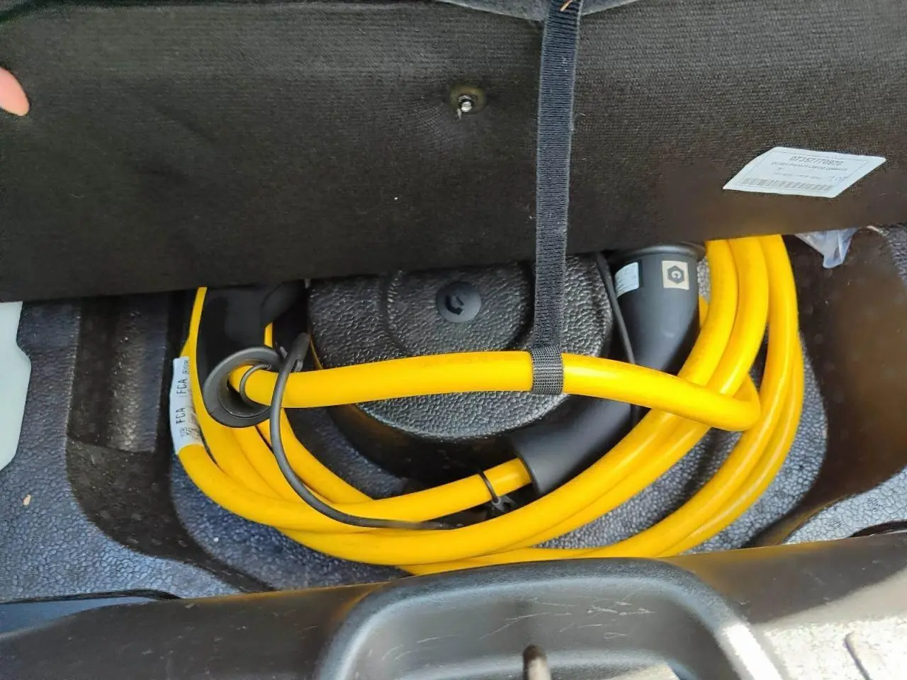 Gros plan sur le câble de recharge jaune rangé dans le coffre de la FIAT 500 électrique blanche, version 2024.