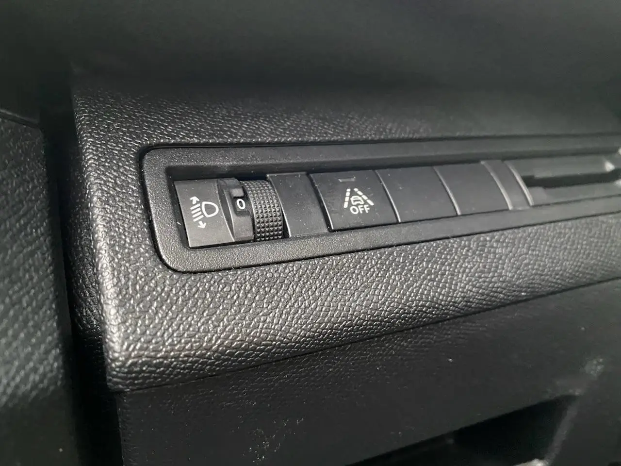 Gros plan sur les commandes de réglage des phares et de l'aide à la conduite dans l'habitacle d'un Peugeot 3008 gris platinium.
