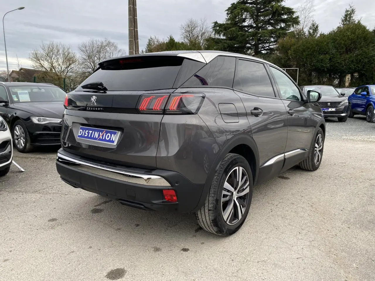 Vue 3/4 arrière droite d'un Peugeot 3008 gris platinium avec feux arrière à effet griffes et vitres teintées.