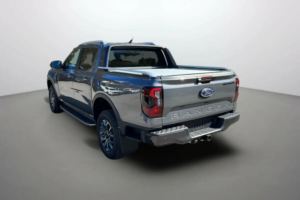 Ford Ranger 3.0 V6 240 Wildtrak Plus gris carbone vu en 3/4 arrière droit avec benne couverte et logo distinctif.