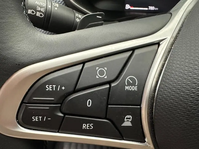Gros plan sur les commandes au volant côté gauche du Renault Arkana 2025, boutons de régulateur et mode de conduite visibles.