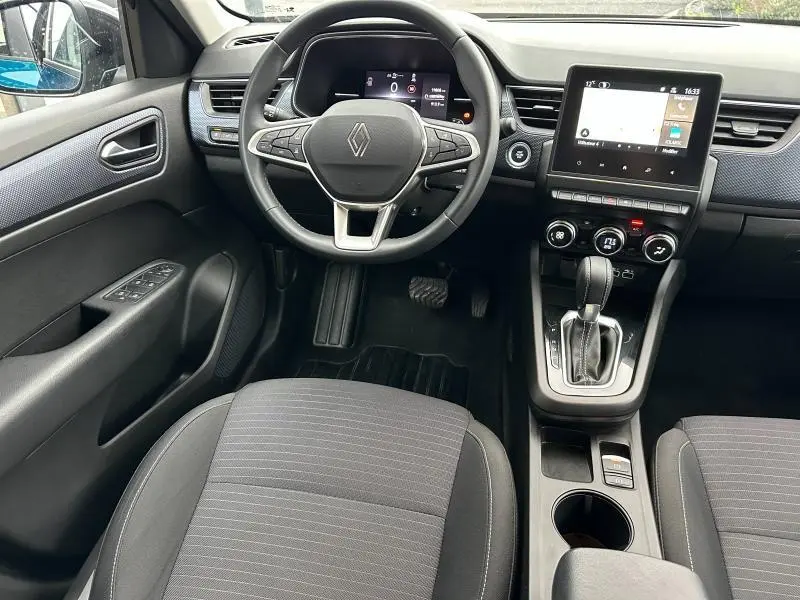 Vue intérieure avant du Renault Arkana 2025, tableau de bord moderne avec écran tactile et volant multifonction.