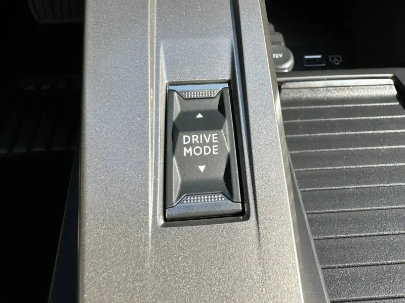 Gros plan sur le bouton Drive Mode noir intégré dans la console centrale gris métallisé du Peugeot 308 1.5 BlueHDi 2025.