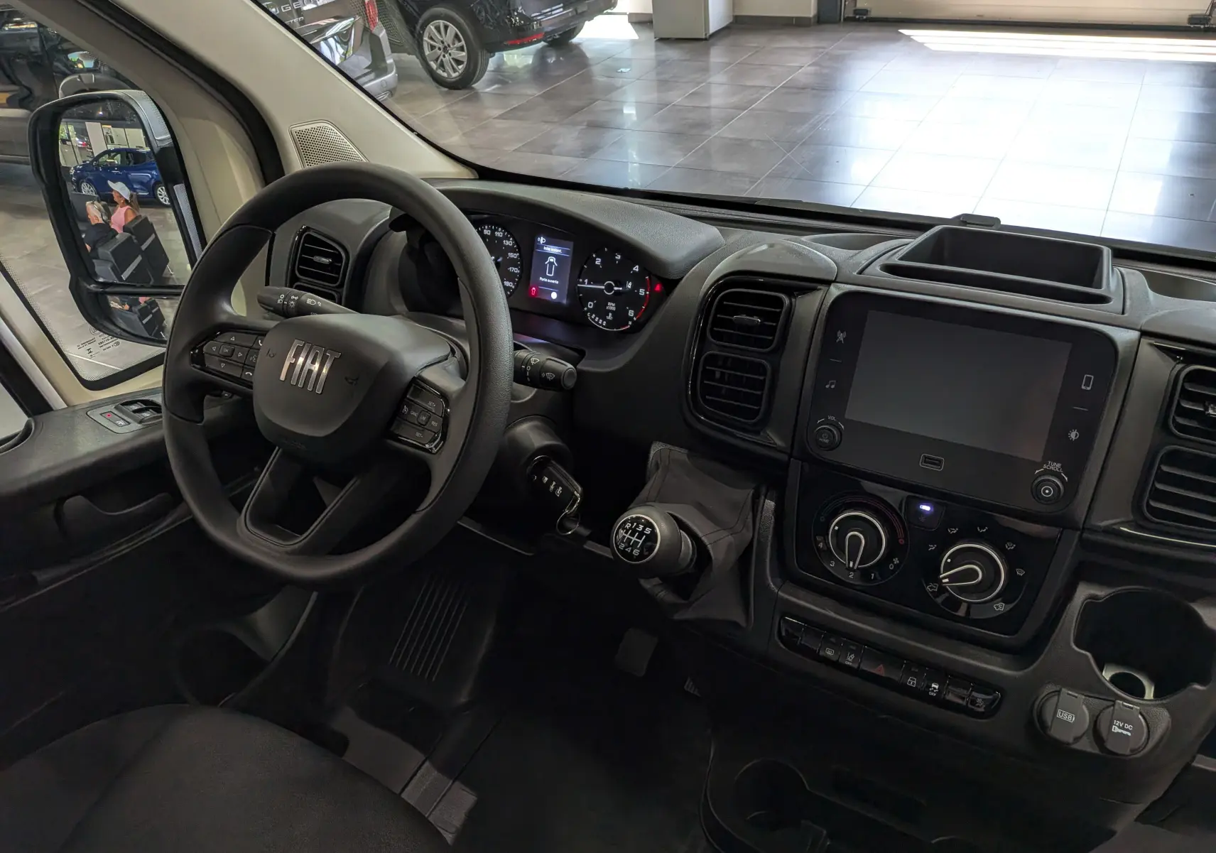 Vue intérieure côté conducteur du Fiat Ducato Fourgon blanc 2026, volant multifonction et tableau de bord avec écran tactile.