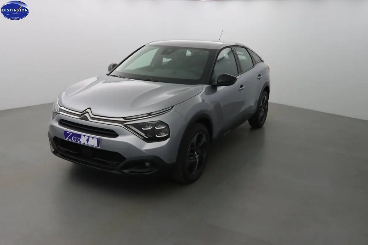 Citroën C4 gris Artense métal vue 3/4 avant droit dans un studio lumineux, jantes noires visibles.