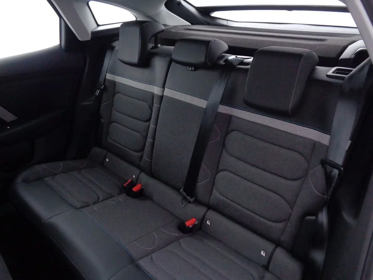 Banquette arrière en tissu gris foncé avec ceinture de sécurité noire dans une Citroën C4 2023 vue de côté intérieur.