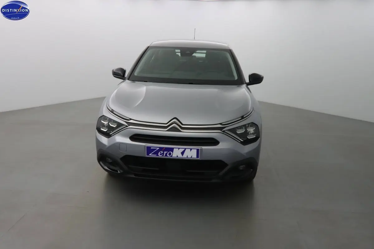 Citroën C4 gris Artense métal vue de face dans un studio, mettant en valeur ses phares LED et sa calandre distinctive.