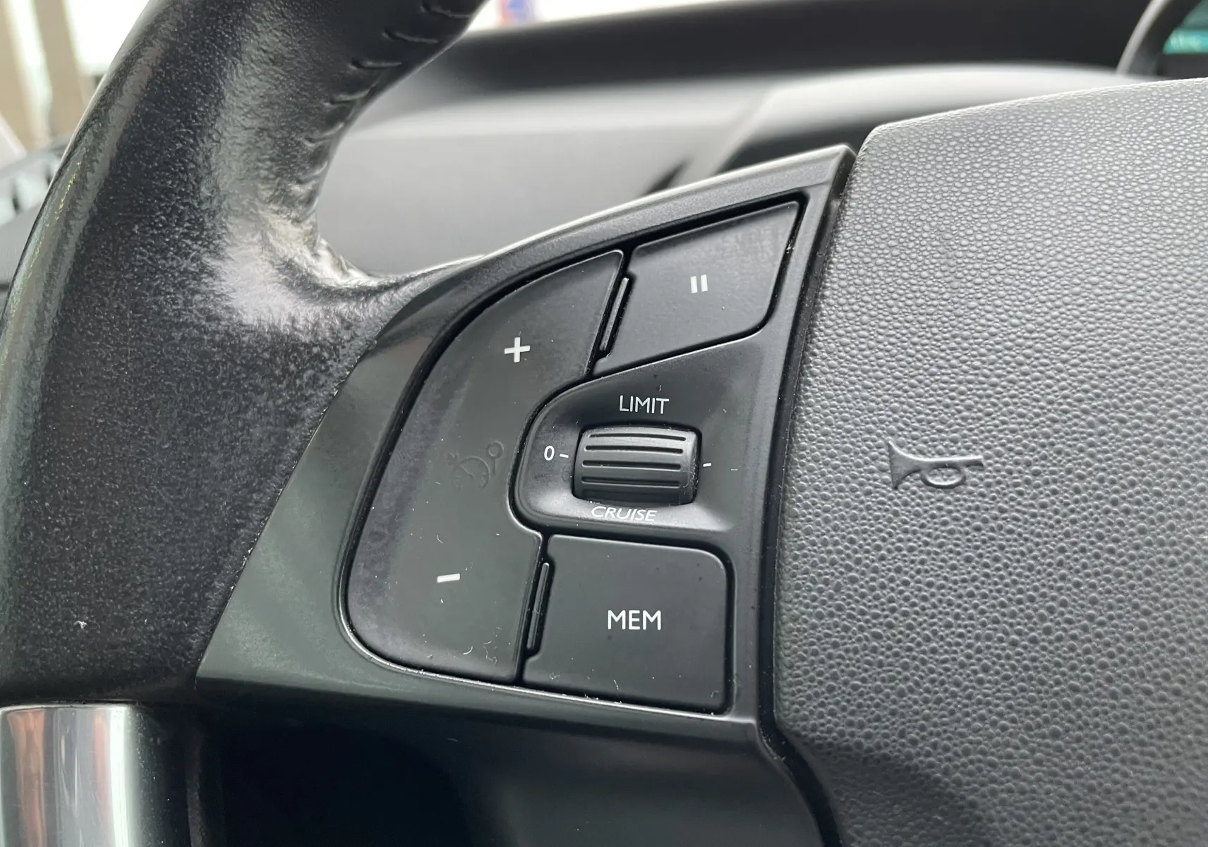 Gros plan sur les commandes de régulateur de vitesse au volant noir du Citroën Grand C4 Picasso gris 2018.