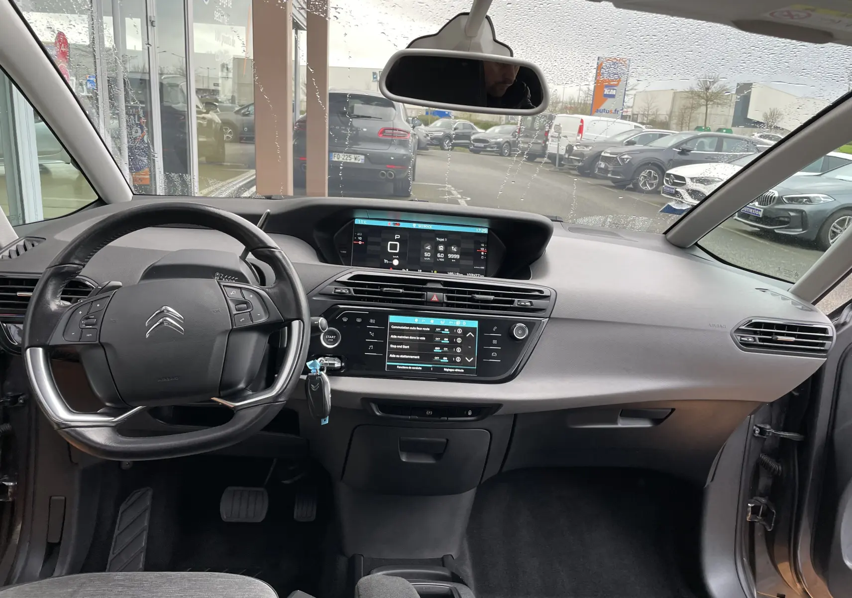Vue intérieure avant du tableau de bord gris du Citroën Grand C4 Picasso 2018 avec écran tactile et volant multifonction.